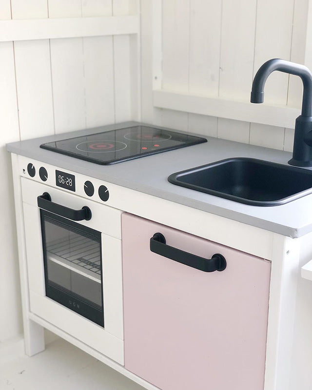 Grå bänkskiva, svarta detaljer och en rosa lucka