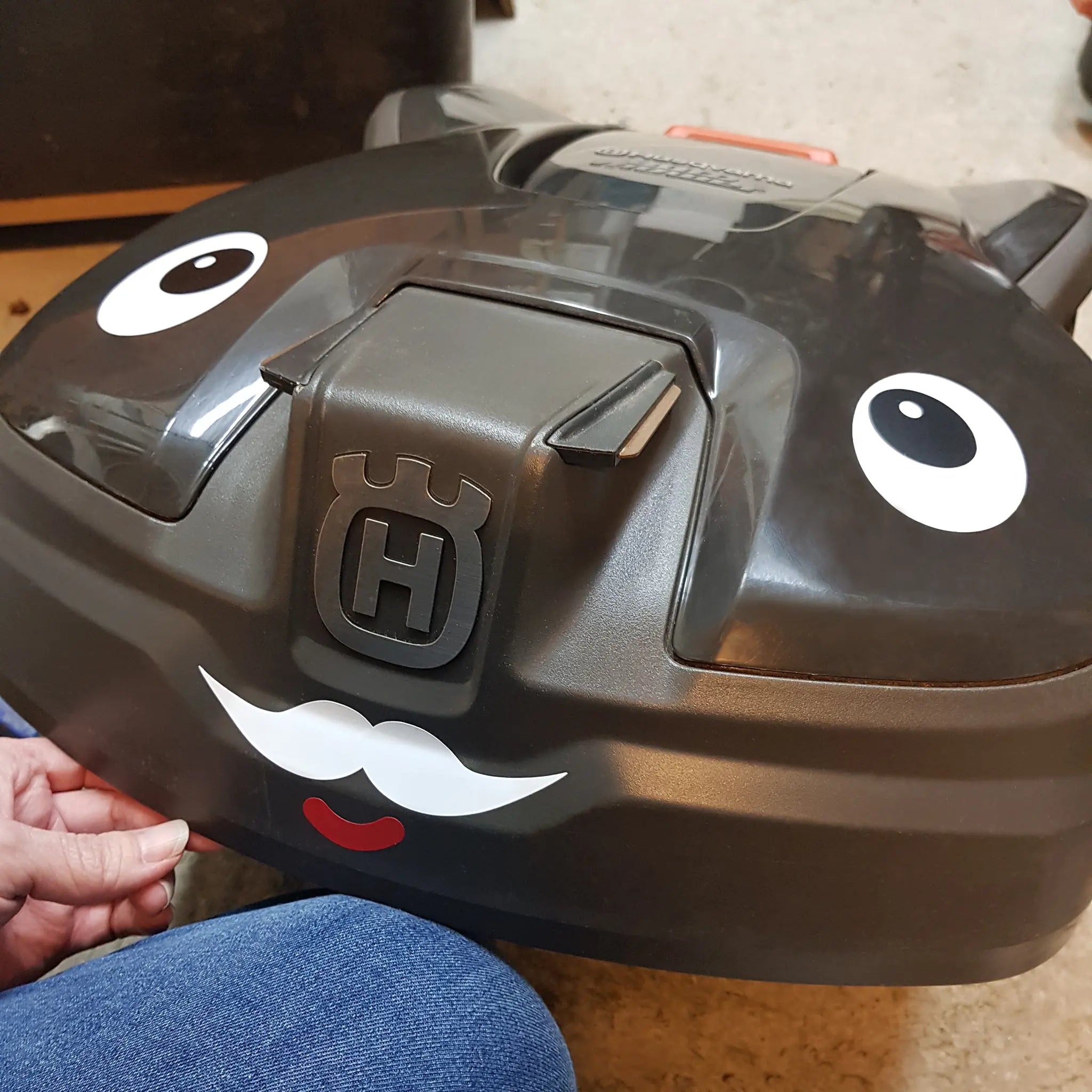 Närbild på robotgräsklipparen Conny som fått ögon, mun och mustasch från Kulform