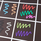 Prov på hur kritpennorna i setet med 8 klara färger ser ut mot en svart planeringstavla med frontskydd i plexiglas.