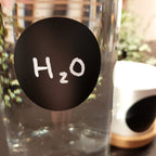 Rund svart griffeletikett med texten H2O på en flaska