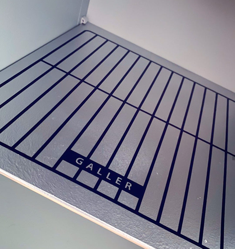 Ugnsgaller i svart på ett silverfärgat hyllplan